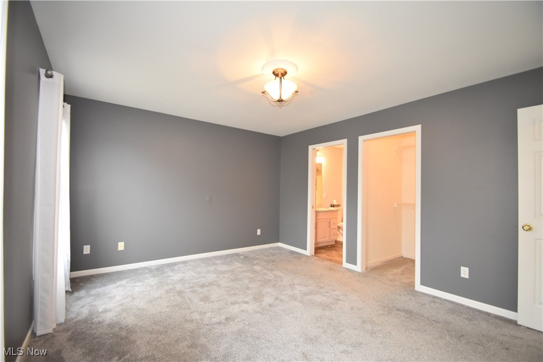 603 South Raccoon Road, Unit 49 Youngstown, OH 44515 - Photo 14 of 27 Unfurnished bedroom featuring a walk in closet, ensuite bath, carpet, and baseboards