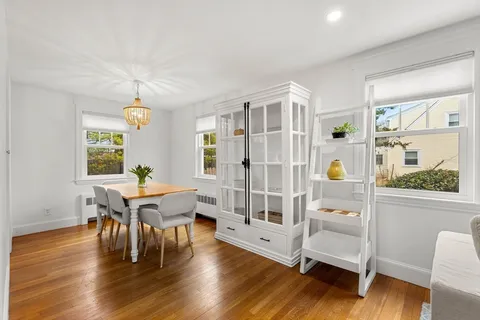 a dining room with wooden floor a chandelier a glass table and chairs