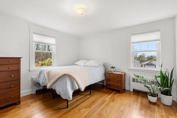 a bed sitting in a bedroom next to a window with potted plant