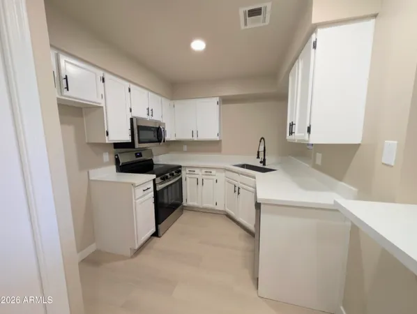 a kitchen with white cabinets sink and stainless steel appliances