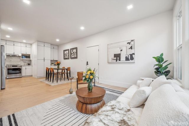 a living room with furniture and a dining table with wooden floor