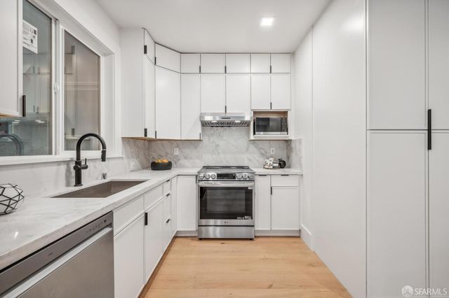 a kitchen with stainless steel appliances granite countertop a stove sink and cabinets