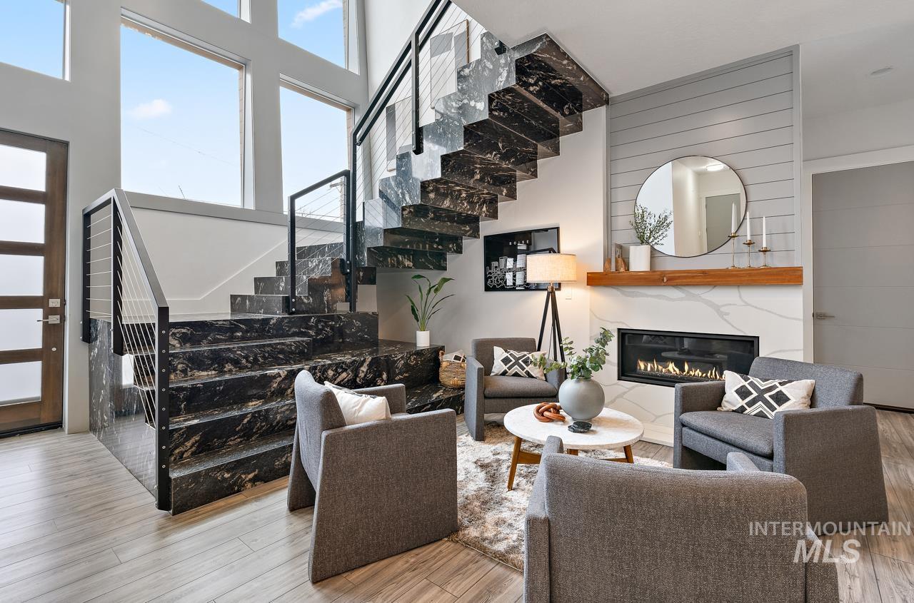 599 West Warren Street Boise, ID 83706 - Photo 6 of 41 Open-concept living space showcasing a striking dark stone staircase with cable railings, a contemporary fireplace with a white surround and wood mantel, shiplap accent wall, and light wood-finish flooring