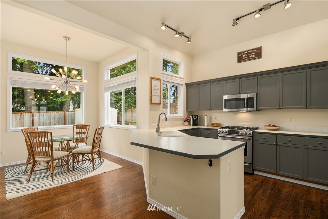 909 Graham Avenue Northeast Renton, WA 98059 - Photo 10 of 32 a kitchen with stainless steel appliances granite countertop a stove a sink a microwave refrigerator and chairs