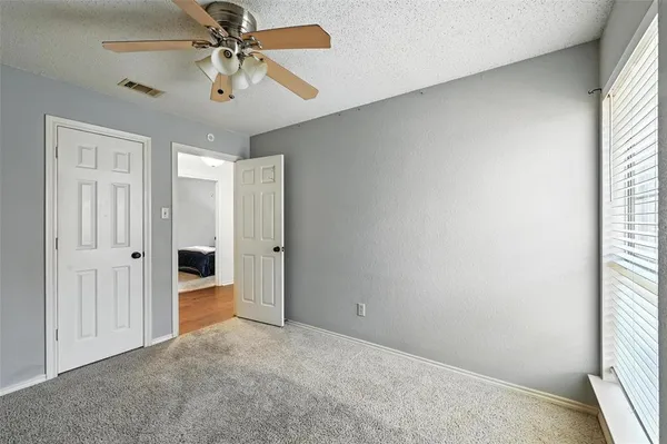 an empty room with windows and fan