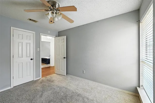 an empty room with windows and fan