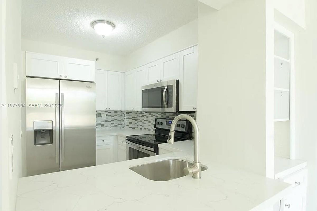 a kitchen with stainless steel appliances granite countertop a refrigerator and a sink