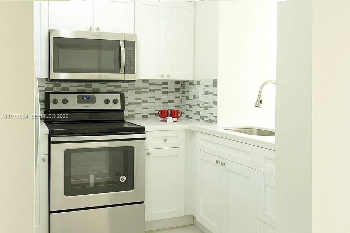 546 Southwest 1st Street, Unit 404 Miami, FL 33130 - Photo 2 of 9 a kitchen with stainless steel appliances white cabinets and a stove