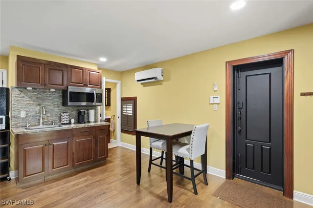 a kitchen with stainless steel appliances granite countertop a stove top oven a sink dishwasher a dining table and chairs with wooden floor