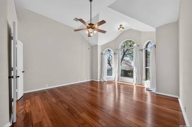 a view of an empty room with window and wooden floor