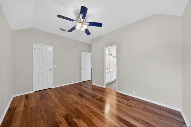 an empty room with wooden floor fan and windows