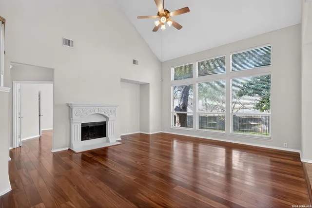 a view of empty room with wooden floor and fan