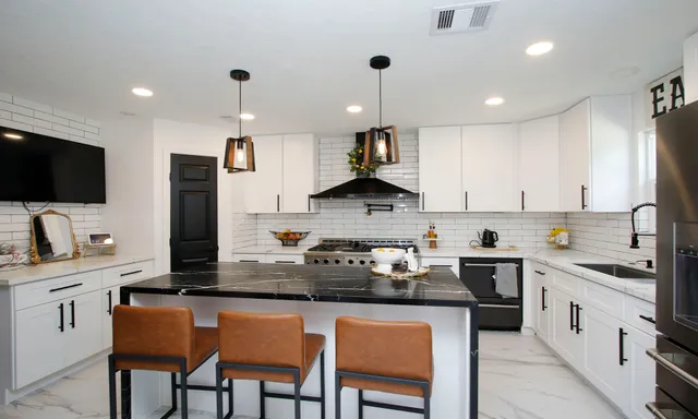 a kitchen with stainless steel appliances granite countertop a sink a stove a refrigerator cabinets and chairs