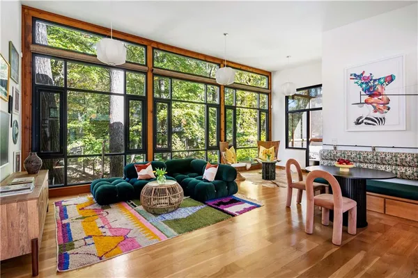 a view of a dining room with furniture one side kitchen view and wooden floor