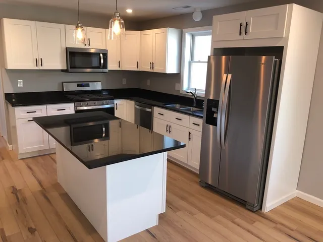 a kitchen with stainless steel appliances granite countertop a refrigerator a sink a stove a microwave and wooden cabinets