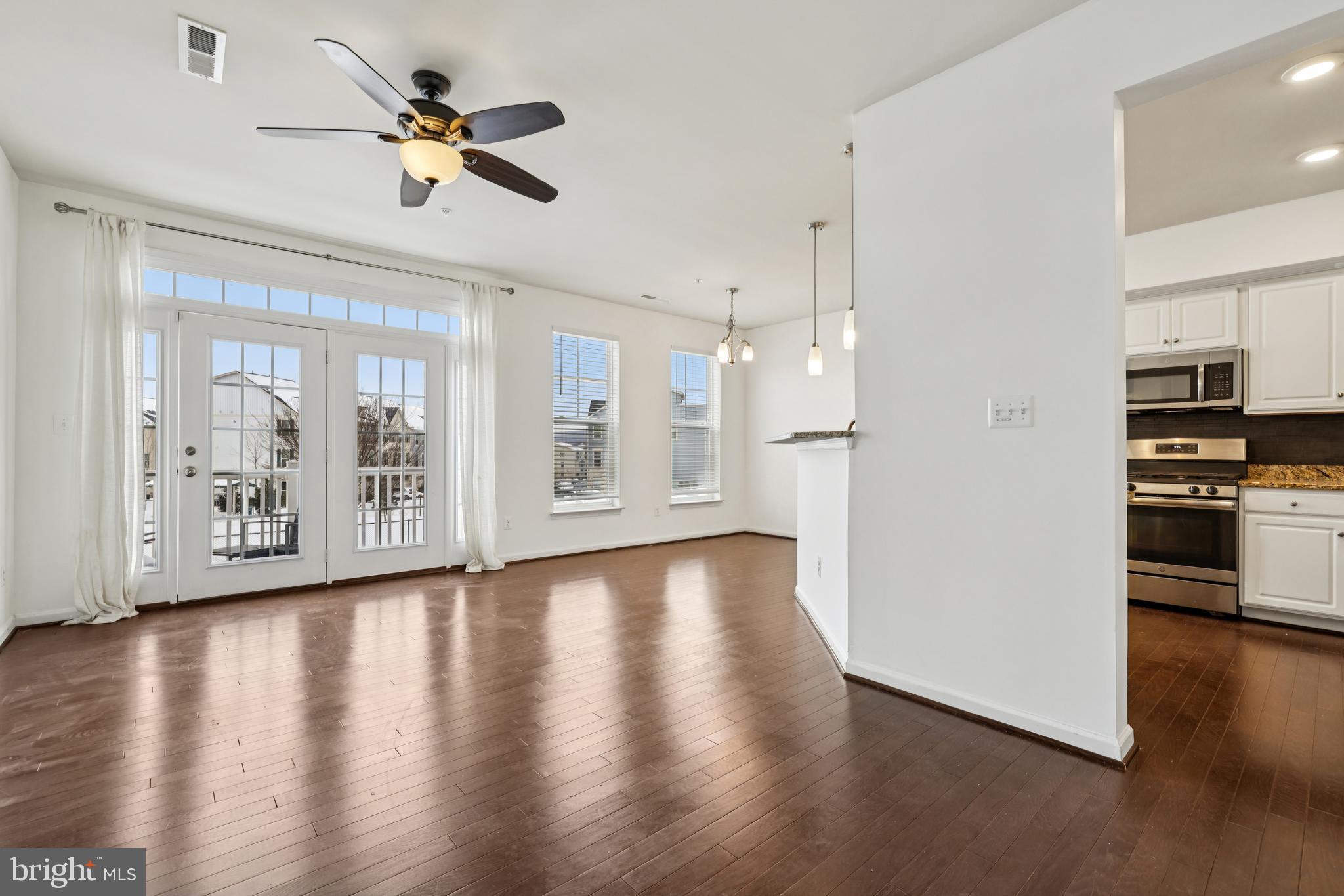 5841 Bella Marie Way Frederick, MD 21703 - Photo 5 of 45 a view of an empty room with wooden floor and a kitchen