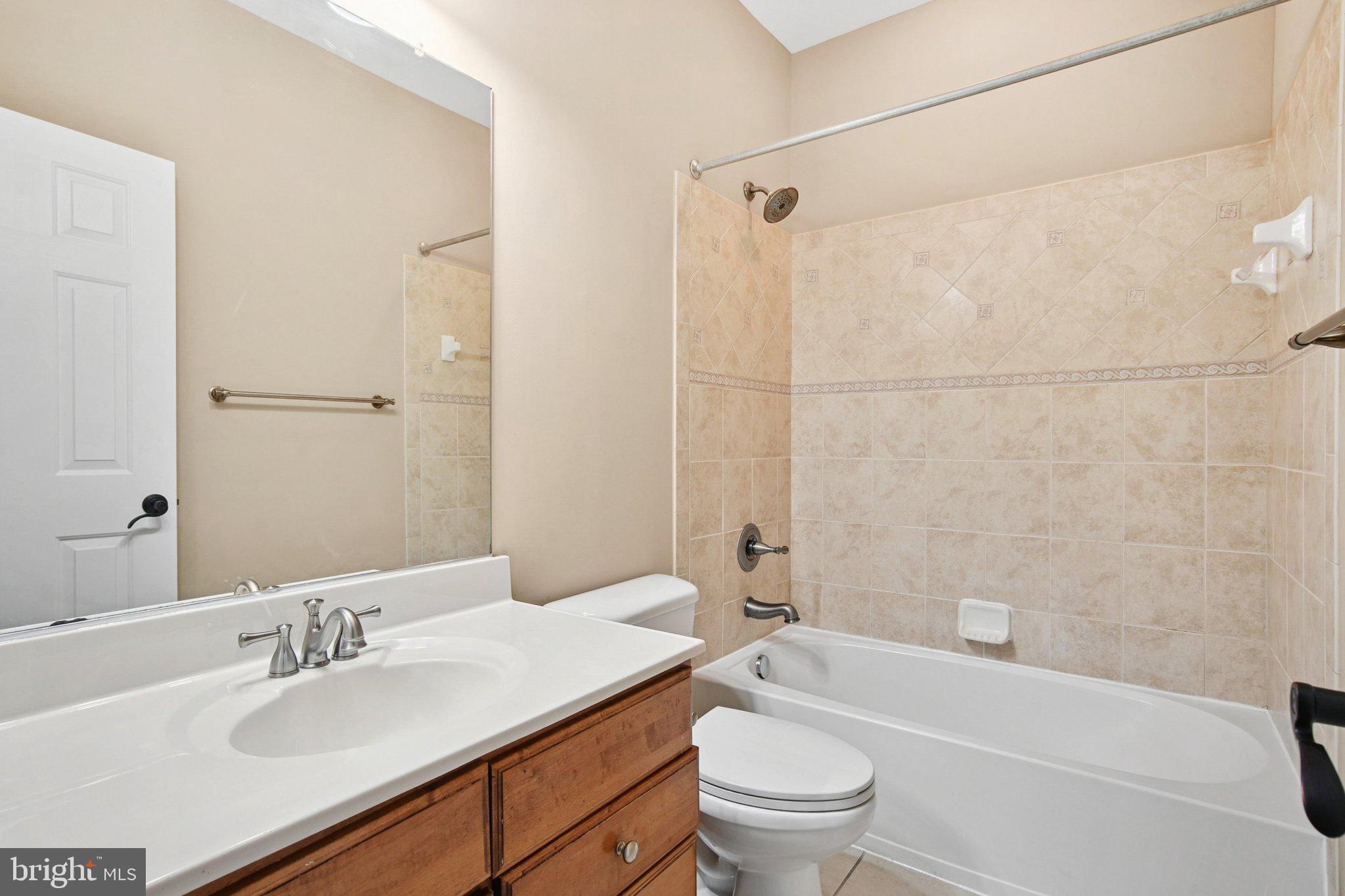 302 Appleby School Road Cambridge, MD 21613 - Photo 13 of 28 a bathroom with a granite countertop sink a toilet a mirror a bathtub and shower