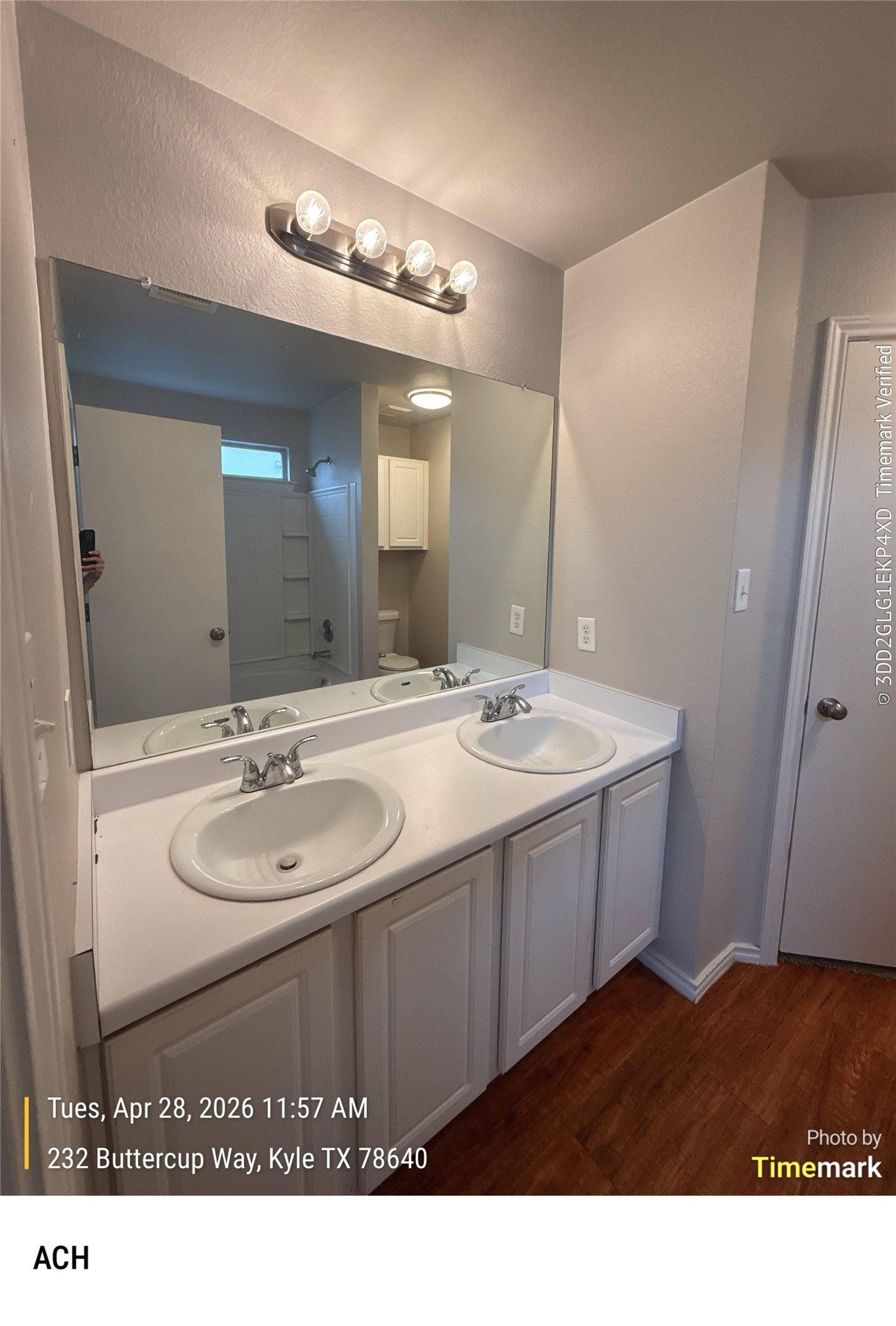 232 Buttercup Way Kyle, TX 78640 - Photo 11 of 17 Dual vanity featuring white cabinetry, integrated sinks, a white countertop, and wood-finish flooring