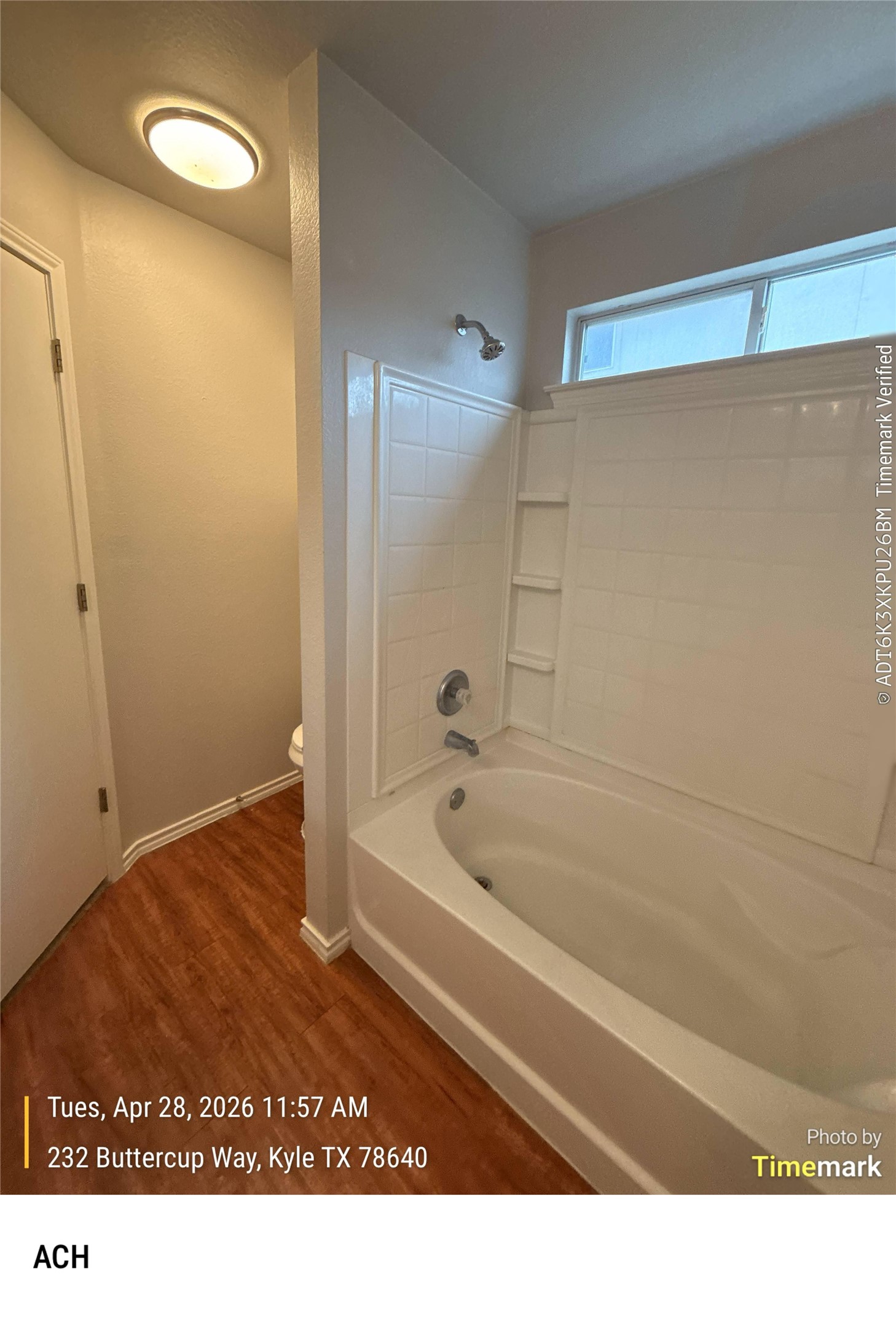 232 Buttercup Way Kyle, TX 78640 - Photo 12 of 17 Bathroom featuring a white tub/shower combination with integrated shelving, wood-finish flooring, a contemporary overhead light fixture, and a frosted window providing natural light
