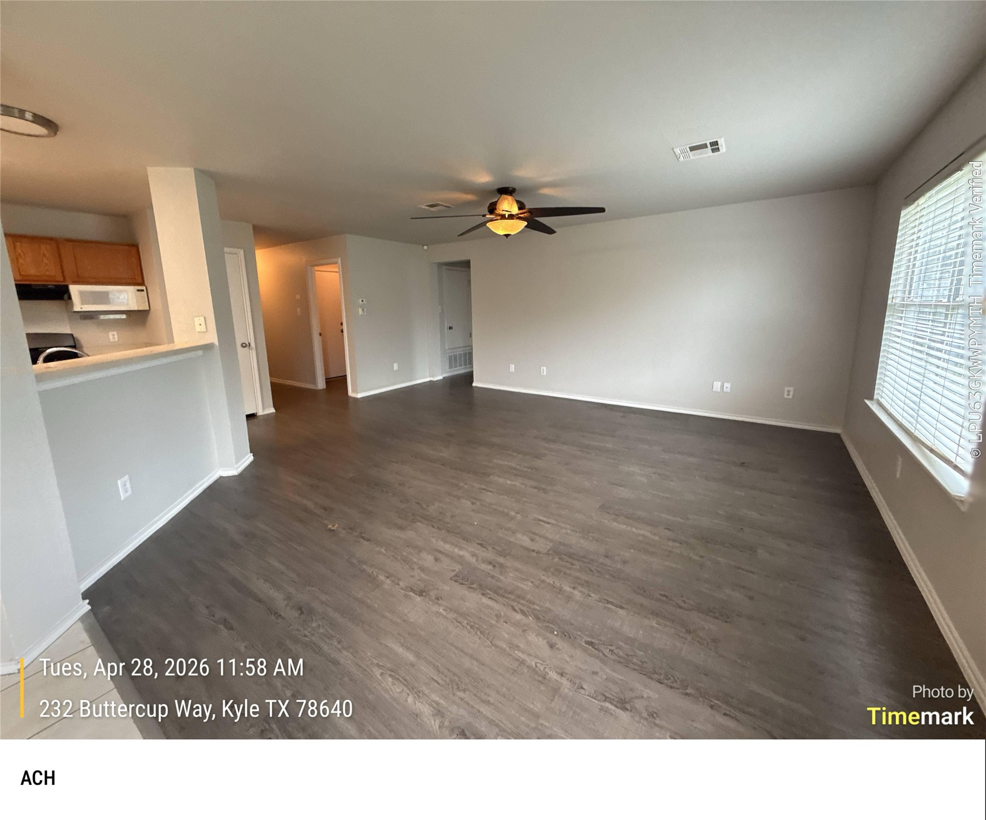 232 Buttercup Way Kyle, TX 78640 - Photo 3 of 17 Spacious living area featuring wood-finish flooring, neutral wall tones, and a ceiling fan with integrated lighting