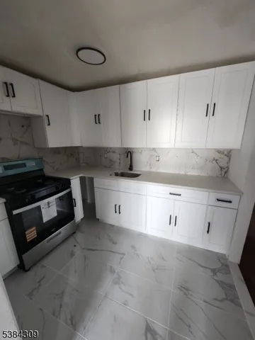 a kitchen with granite countertop white cabinets and white appliances