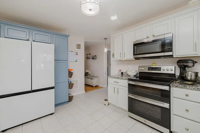 a kitchen with stainless steel appliances a refrigerator stove and white cabinets