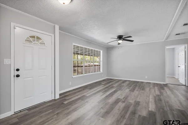 a view of an empty room with a window and wooden floor