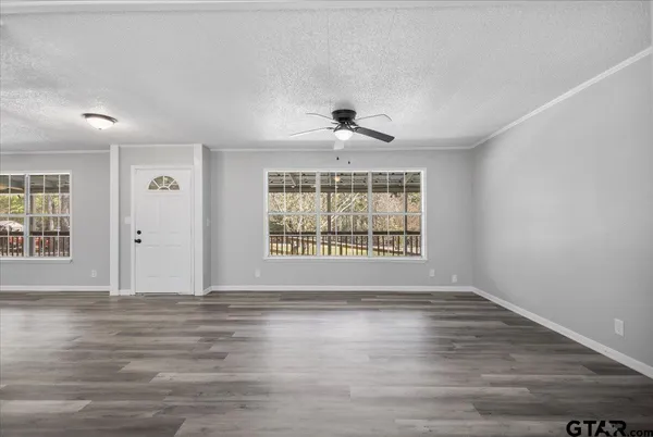 a view of an empty room with a window and wooden floor