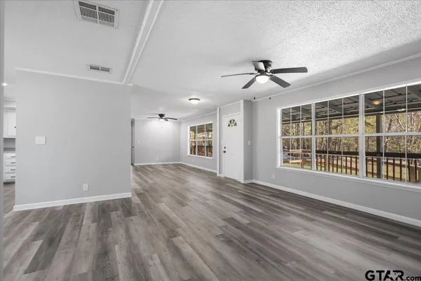 a view of an empty room with a window and wooden floor