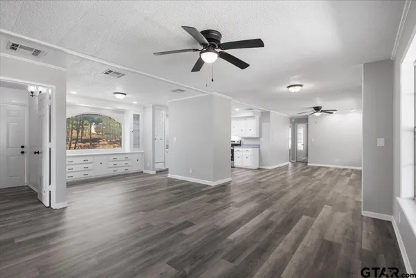 a view of empty room with wooden floor and ceiling fan