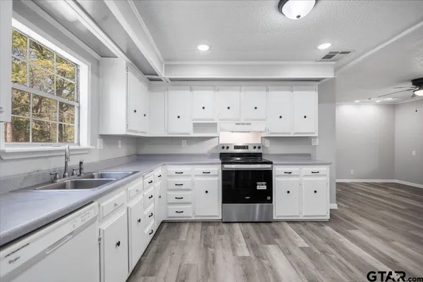 a kitchen with granite countertop a stove a sink and a refrigerator