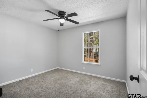 an empty room with windows and fan