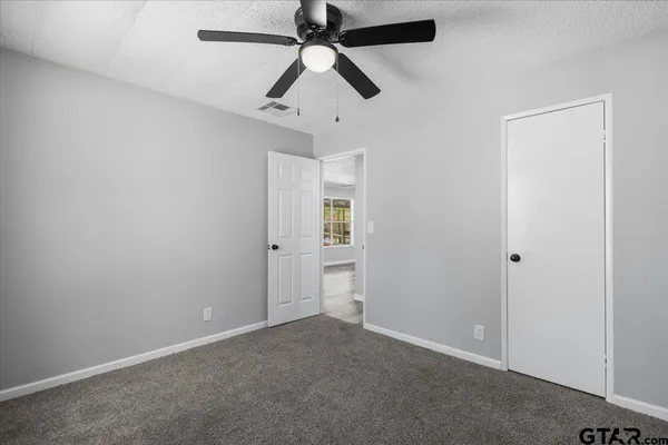 an empty room with closet and a ceiling fan