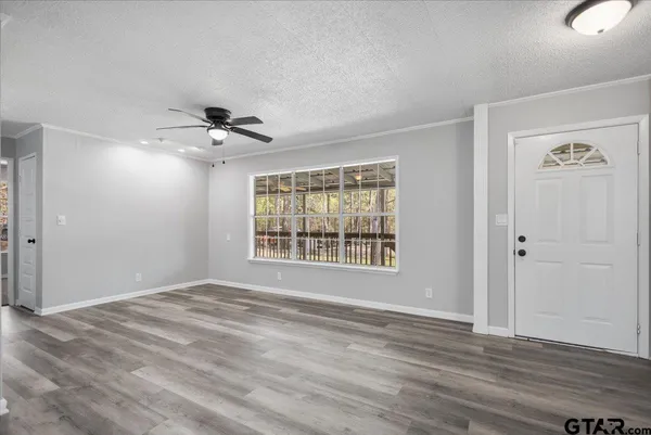 a view of an empty room with a window and wooden floor