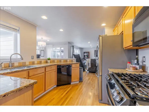 a kitchen with stainless steel appliances granite countertop a stove a sink dishwasher and a microwave with wooden floor