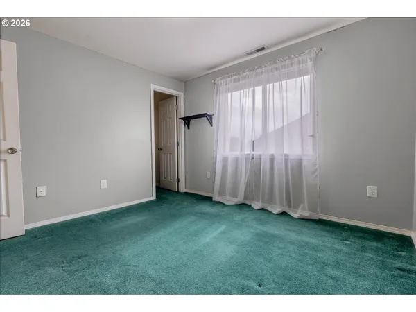 a view of an empty room with window and stairs