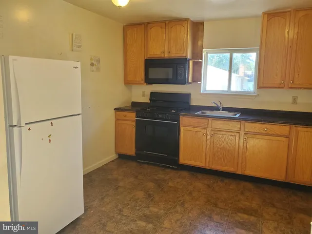 a kitchen with stainless steel appliances granite countertop a refrigerator a stove a sink and a window