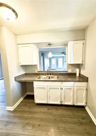a view of a kitchen with kitchen island a sink wooden floor and a counter top space