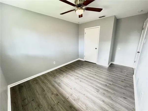 an empty room with wooden floor and ceiling fan