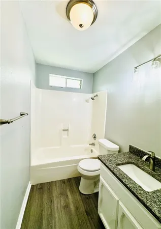 a bathroom with a granite countertop sink toilet a mirror and bathtub