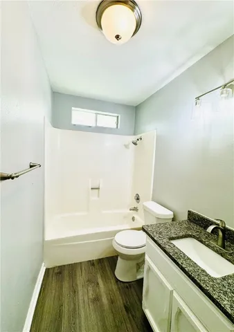 a bathroom with a granite countertop sink toilet a mirror and bathtub