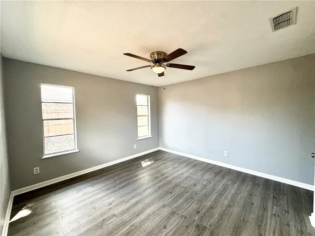 an empty room with window and a ceiling fan