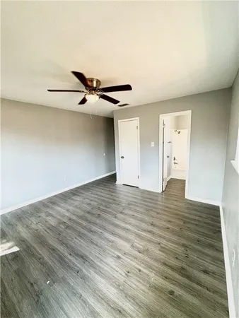 a view of an empty room with wooden floor and a ceiling fan