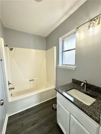 a bathroom with a granite countertop sink and a bathtub