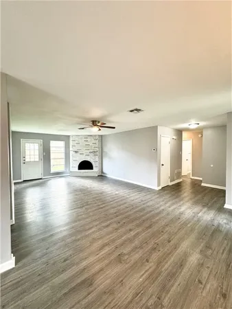 an empty room with fireplace wooden floor and windows