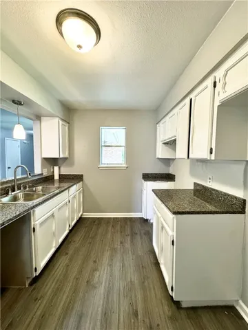 a large kitchen with granite countertop a stove top oven a sink a counter space and cabinets