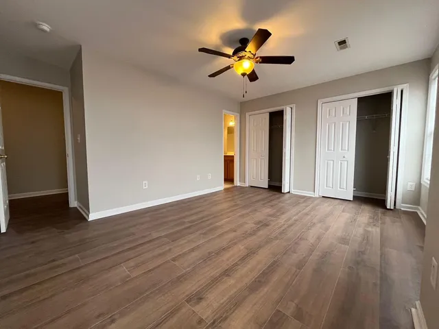 an empty room with wooden floor and chandelier fan