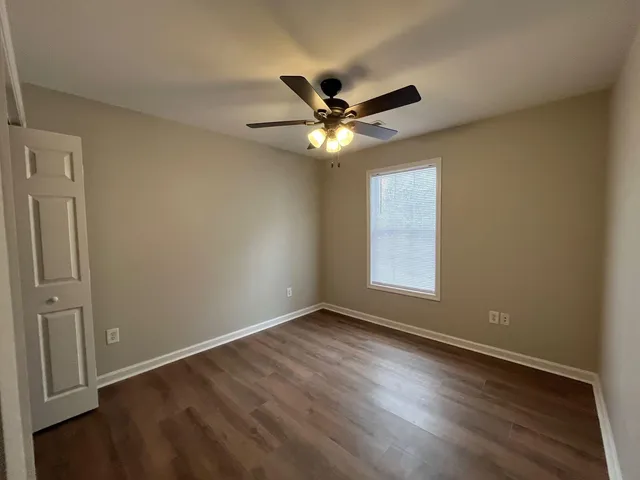 a view of an empty room with window and wooden floor