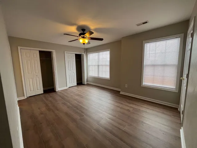 an empty room with windows and chandelier fan