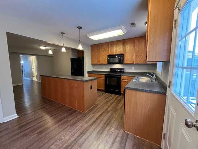 a kitchen with stainless steel appliances a microwave a stove a sink cabinets and wooden floor